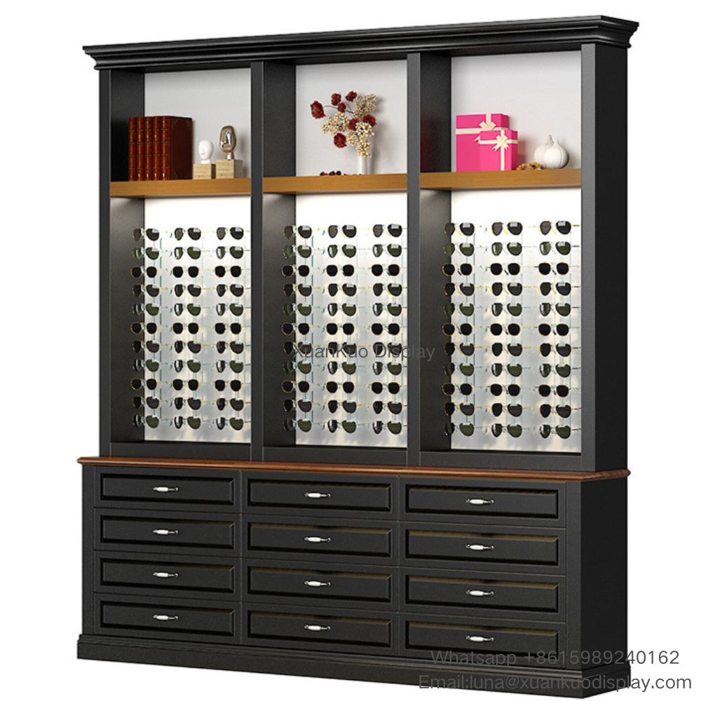 Tall vertical vintage wooden optical shop cabinet constructed with dark solid wood and light wood decorative trim. Three separated display zones fitted with vertical slotted back panels to hang optical frames and sunglasses. Upper open shelf provides space for ornaments, books and brand decorations. The bottom section contains 12 large-capacity classified lockable drawers for storing lens cases, spare frames and eyewear accessories. Classic retro design fits traditional and vintage style optical retail stores.