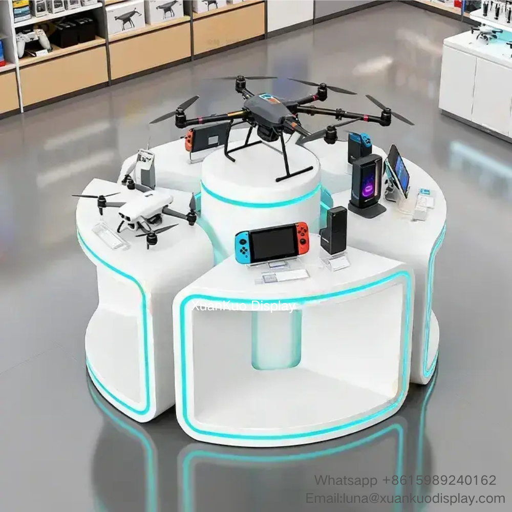 modern white segmented circular electronics display island, curved sector modules with blue ambient LED light strips, hollow open front design, multi-platform demo zones for drones, game consoles and digital gadgets, modular combination central display stand for tech retail shop
